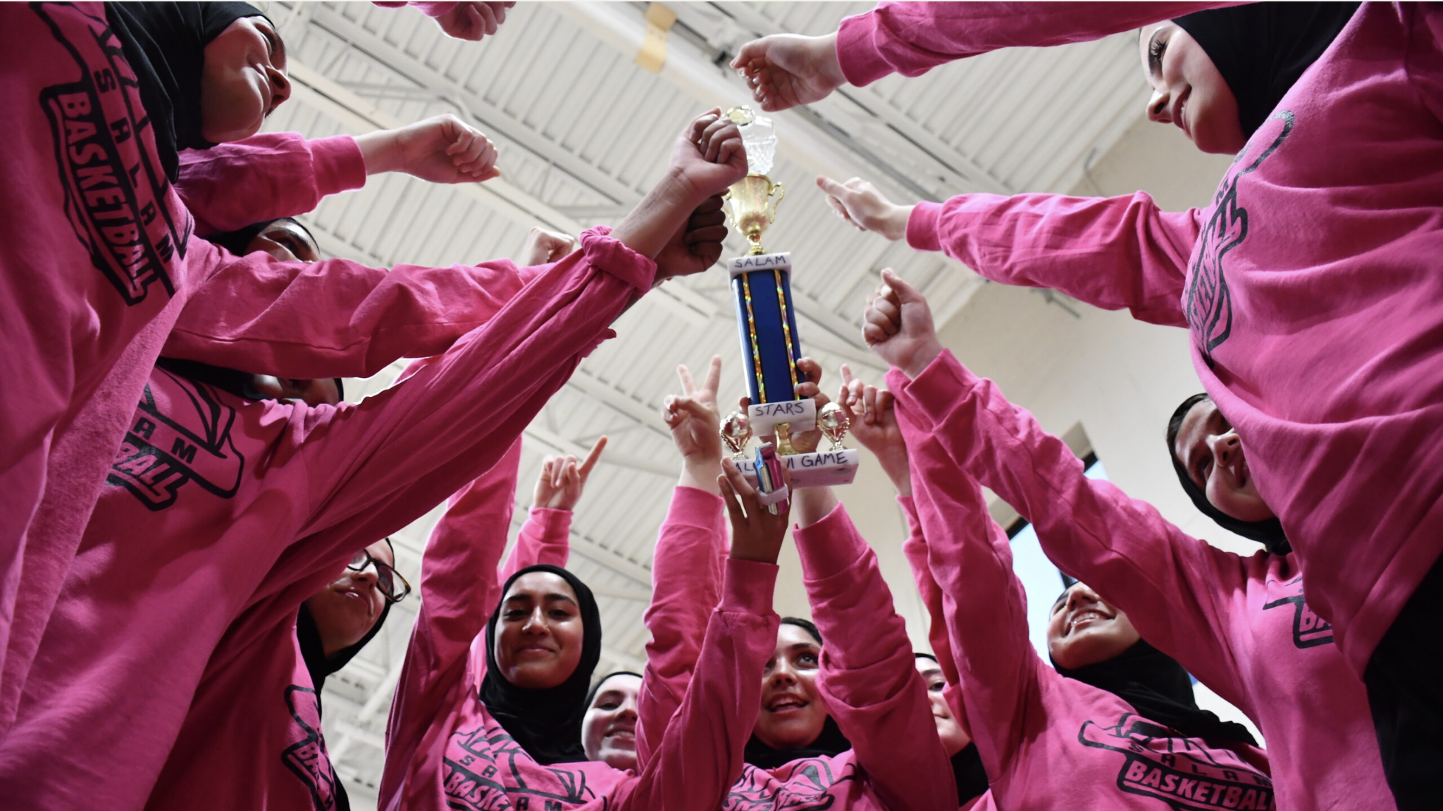 Girls wearing pink hold a trophy